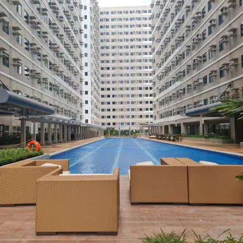 a large building with a swimming pool in front of it at Cozy STUDIO for 4 Guests in Dasmariñas