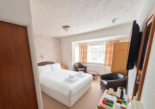 a hotel room with a white bed and a chair at The Mayfair in Skegness
