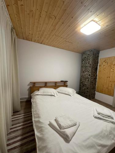 a bedroom with a large bed with two towels on it at CABANA MARIA-PETRIMANU in Ciungetu
