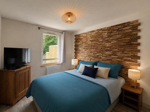 a bedroom with a blue bed and a brick wall at Appartement in Vielle-Aure