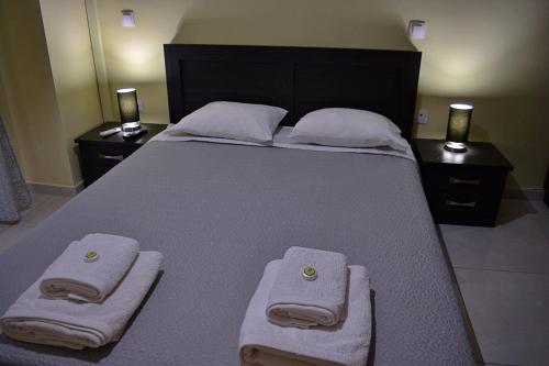 a large bed with two towels on it with two night stands at VILLA IN THE OLIVE TREES Galaxidi in Galaxidi