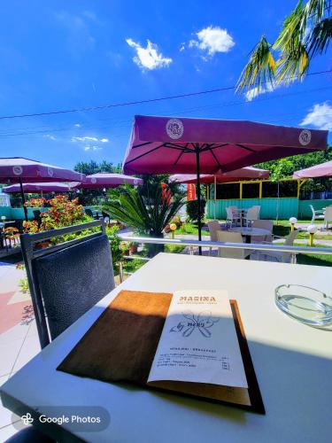 a book sitting on top of a table with an umbrella at Hotel Bar Restorant Marina in Mjedë