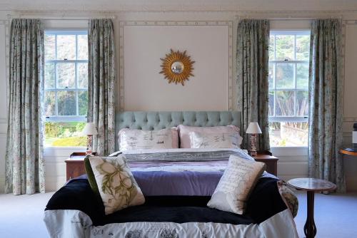 a bedroom with a bed with a blue headboard and windows at Fernside Estate and Gardens in Fernside