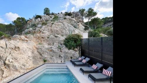 a swimming pool with lounge chairs and a mountain at The One in Port d'Andratx