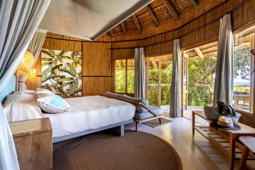 a bedroom with a large bed and windows at Thonga Beach Lodge in Mabibi
