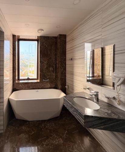 a bathroom with a large tub and a sink at Israel Ori Hotel in Yerevan