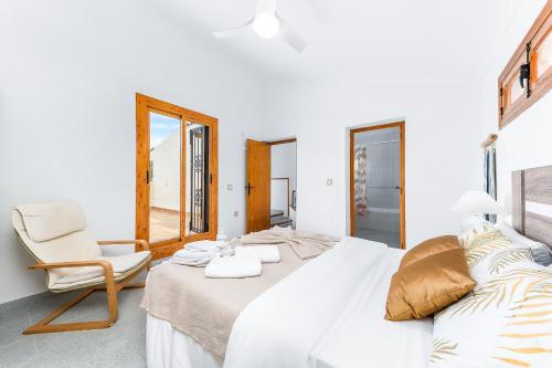 a bedroom with a large white bed and a chair at Chalet Mayor Zenia Beach in Orihuela