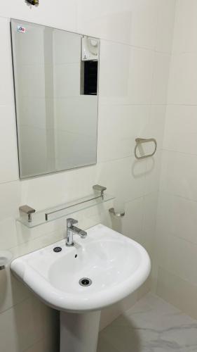 a white bathroom with a sink and a mirror at Grand Stay Hotel in Seeduwa