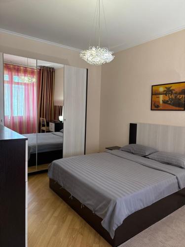 a bedroom with a large bed and a chandelier at Иссык-Куль,Частный таунхаус-всего минута до пляжа в ЦО "Karven Four Seasons" Issyk-Kul in Chon-Sary-Oy