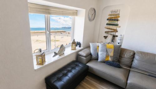 a living room with a leather couch and a window at Stunning Harbour View Beachfront Apartment Parking in Rhos-on-Sea