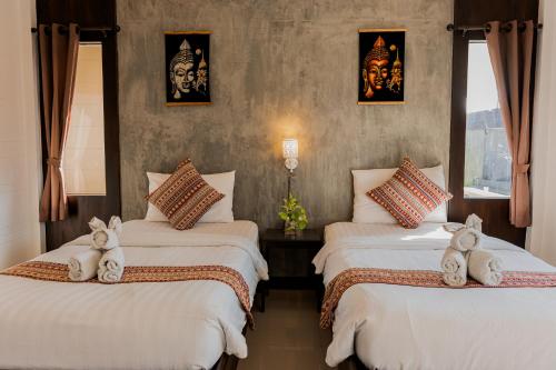 two beds with stuffed animals on them in a room at Thanawong Pool Villa in Sukhothai