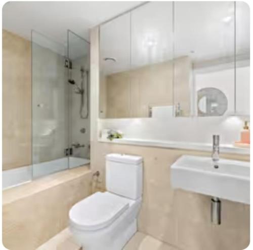 a white bathroom with a toilet and a sink at Olympicpark 12 Free Parking in Sydney