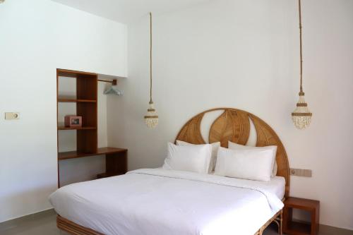 a bedroom with a white bed with a wooden headboard at La Calma Villa in Gili Islands