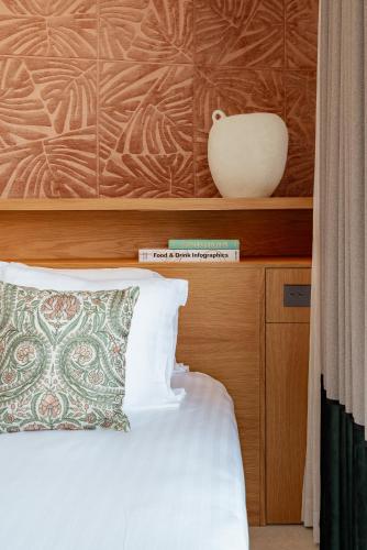 a bed with a pillow and a vase on a shelf at Appart Hôtel Résidence Courcelle in Levallois-Perret