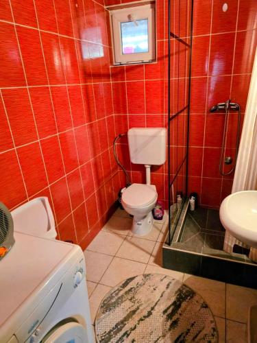 a red tiled bathroom with a toilet and a sink at MiR in Londža