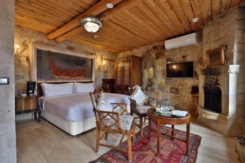 a bedroom with a bed and a table and a tv at Elika Cave Suites Cappadocia, Curio Collection by Hilton in Ortahisar