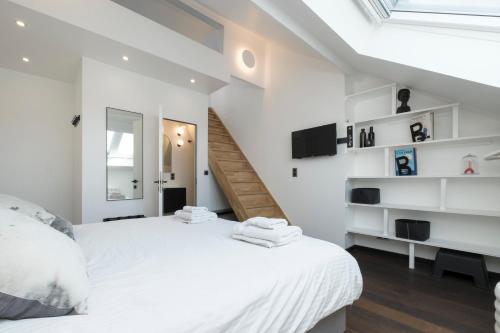 a bedroom with a large white bed and a staircase at Bed & Breakfast La Linière in Brussels