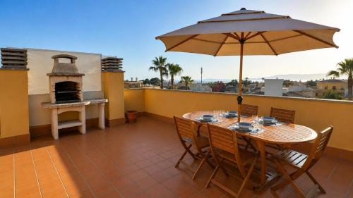 a table and chairs with an umbrella on a balcony at Son Veri LUXURy HOME in Cala Blava