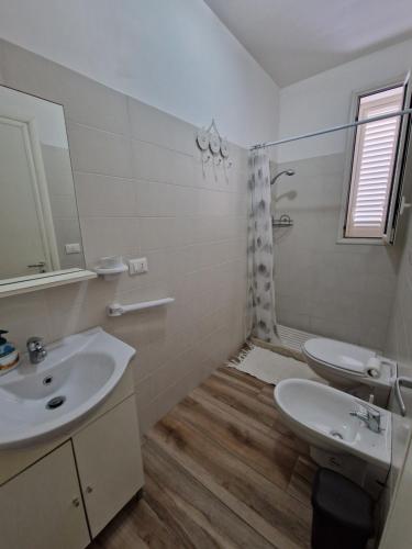 a bathroom with a sink and a toilet and a mirror at B&B Mare di Ricordi Camera in San Foca