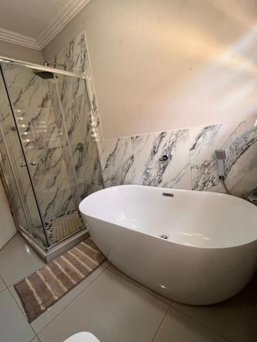 a white bath tub in a bathroom with marble walls at Lamamie Suite Lodge in Thohoyandou