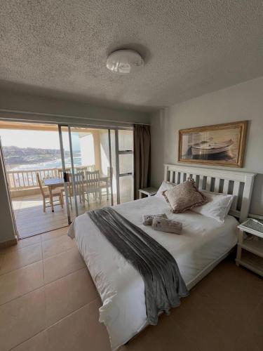 a bedroom with a large white bed with a balcony at Laguna La Crete 33 in Uvongo Beach