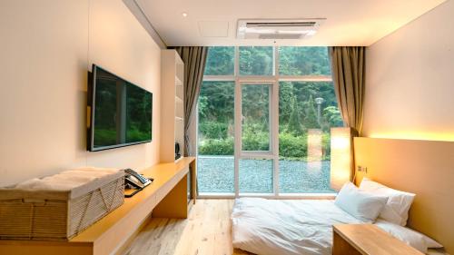 a room with a bed and a large window at Potalaka Naksan Beach Wellness in Yangyang