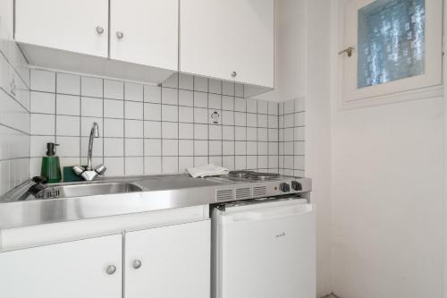 a kitchen with white cabinets and a sink at Villa Milia 2 in Agios Nikitas