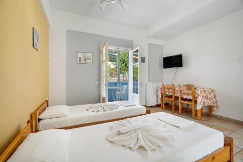 a bedroom with two beds and a dining room at Villa Milia 2 in Agios Nikitas