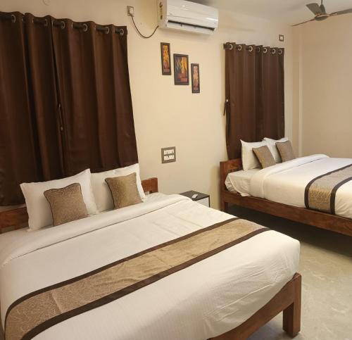 two beds in a hotel room with curtains at Auro Green Villa in Pondicherry