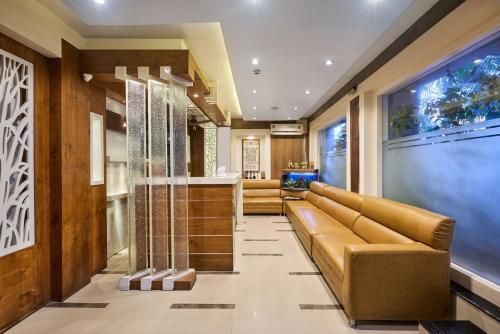 a lobby with a leather couch and a television at Treebo Amber International Mumbai Airport T2 in Mumbai