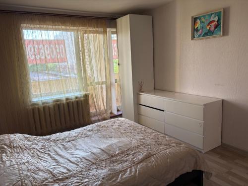 a bedroom with a bed and a dresser and a window at Marsel Odesa in Odesa