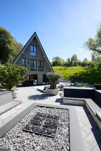 a house with a courtyard with a bench and trees at Chalet NATURTRAUM in Runkel