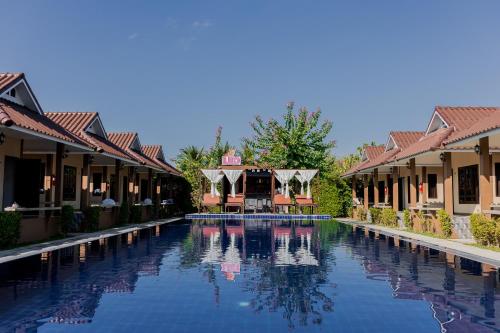 a swimming pool at a resort with houses at Thanawong Pool Villa in Sukhothai