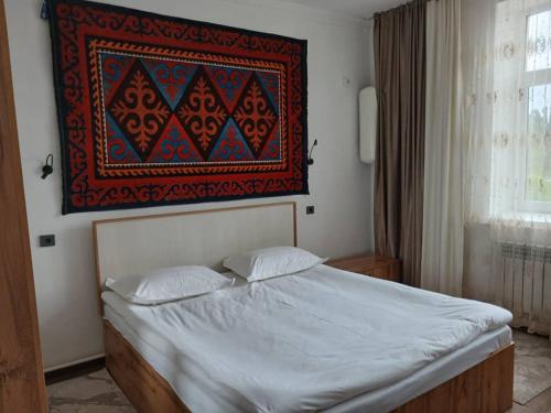 a bed with two pillows and a painting on the wall at Archa Hotel Kochkor in Kochkorka