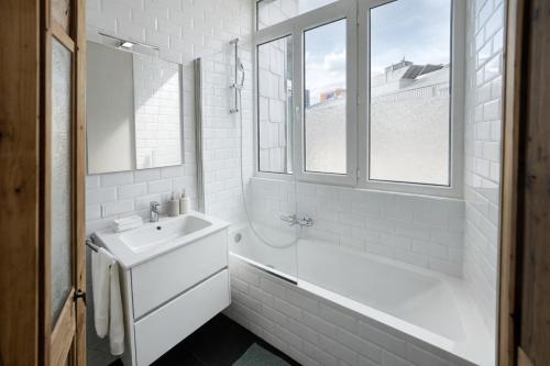 a white bathroom with a sink and a bath tub at Boho Apartments - 2 Bedrooms in Antwerp