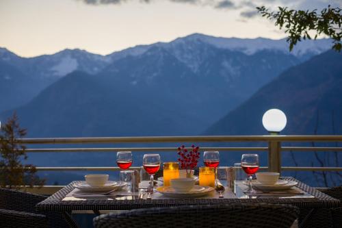 a table with wine glasses on a balcony with mountains at SaffronStays Interstellar in Manāli