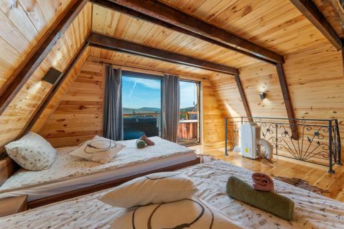 two beds in a room with a large window at Vila Deniri in Zlatibor
