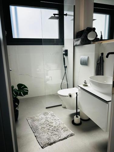 a bathroom with a white toilet and a sink at Olympus Pearl in Skotina