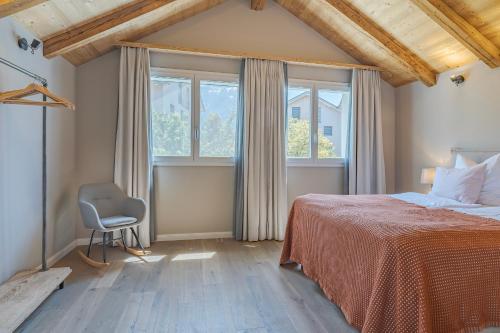 ein Schlafzimmer mit Bett, Stuhl und Fenstern in der Unterkunft Eiche in Interlaken