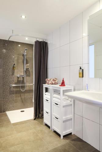 a white bathroom with a sink and a shower at Hôtel Cyano Fréjus-Saint Raphaël in Fréjus
