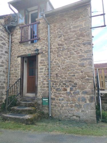 a stone house with a door and a staircase at La maison d'André in Laurière