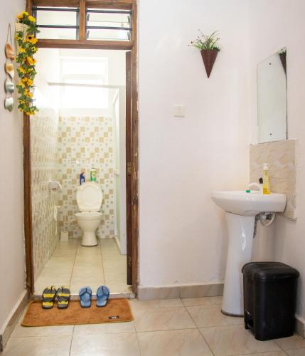 a bathroom with a toilet and a sink with shoes on the floor at Bamburi BnB in Mombasa