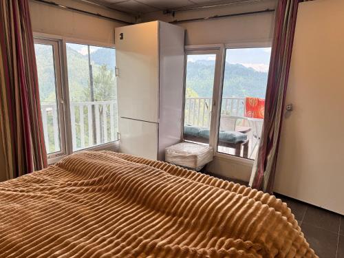 a bedroom with a bed with a view of a balcony at Casa Azul Mountain Resort in Nathia Gali