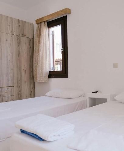 two beds in a room with a window at Iliaxtida apartments II in Grámousa