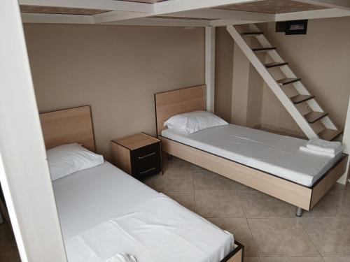 two beds in a small room with a ladder at Proper Apartment in Vlorë