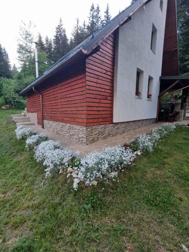a red and white building with flowers in front of it at Star Panzió in Harghita-Băi