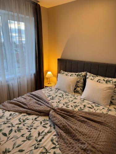 a bedroom with a large bed with pillows and a window at ESSE Apartament in Gulbene