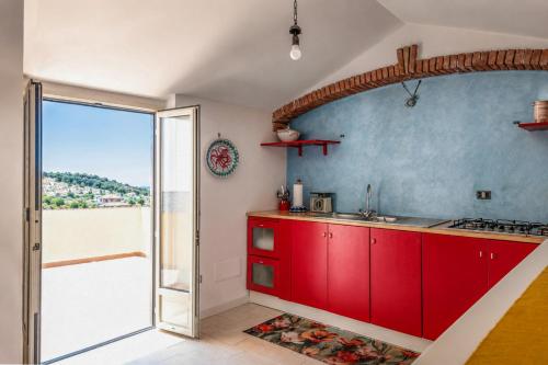 a kitchen with red cabinets and a door to a balcony at Casa Vacanze Panoramics in Acquedolci