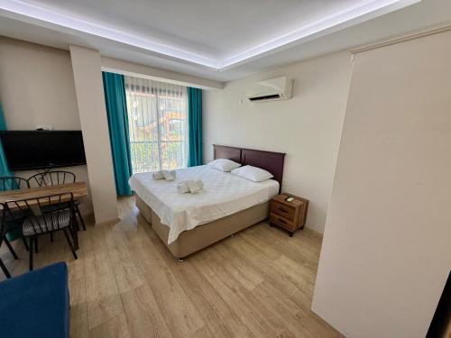 a bedroom with a bed and a table and a window at Arti̇m Apart Hotel in Fethiye