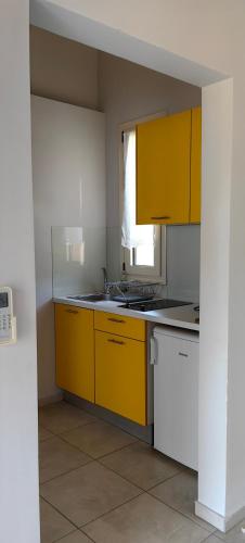a kitchen with yellow cabinets and a window at Zois Apartment in Gliki